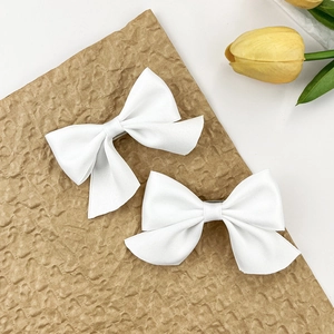 Lot de deux élégantes pinces à cheveux en satin blanc sur fond esthétique de papier kraft