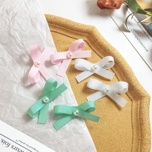 Detailed close-up of ribbon bows with white pearls in pink, white and mint colors