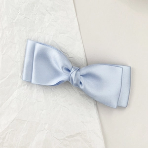Détail d'une pince à cheveux en satin bleu clair avec design double couche et brillant