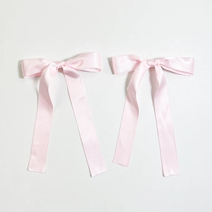 Detail of pink satin bow hair clips with long ribbons in elegant ballet style