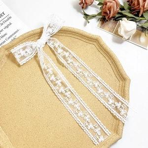 Detail shot of white lace bow hair clip with ribbons on an elegant vintage tray