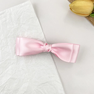 Barrette à cheveux élégante en satin rose avec double nœud sur papier blanc texturé