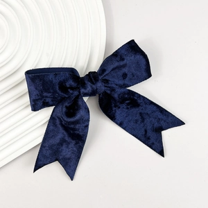 Detail van een marineblauwe fluwelen strik haarclip op een wit decoratief bord