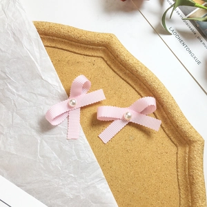 Pair of sweet pink ribbon bow hair clips with pearls on a rustic wooden tray decoration