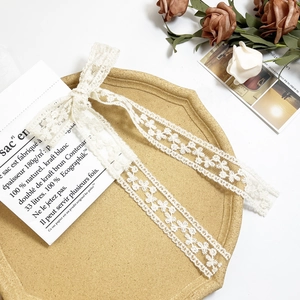 Detailed close-up of white lace ribbon bow with floral cutouts on a vintage card