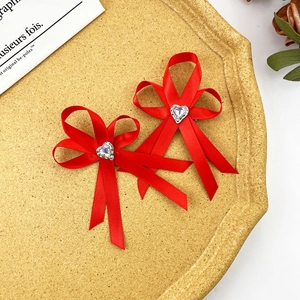 Détail de nœuds à cheveux en satin rouge avec strass en cœur sur un plateau