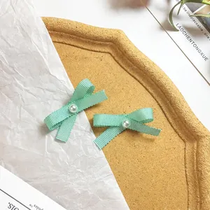 Detail of mint green grosgrain ribbon bow hair clips with white faux pearl centers