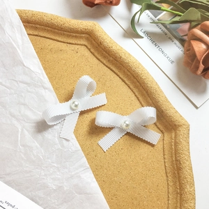 Elegant white ribbon bow hair clips with pearls on a decorative tray for women