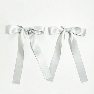 Detail of two silver satin bow hair clips with long ribbons and smooth glossy texture