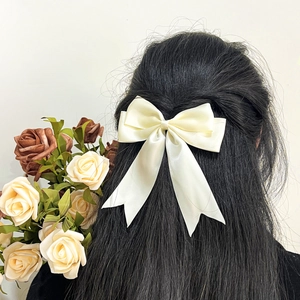 Barrette à nœud en satin crème avec longs rubans portée à l'arrière du modèle