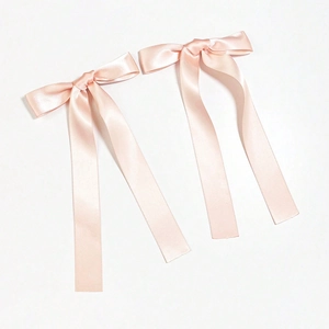 Close-up of a pair of elegant champagne pink satin ribbon bow hair clips with long streamers