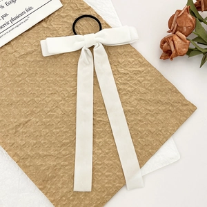 Close-up of a white velvet bow hair tie with long ribbons on a vintage texture background