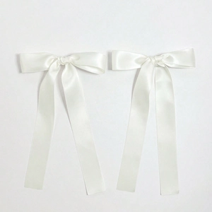 Detail of white satin ribbon bow hair clips with elegant smooth texture and long streamers