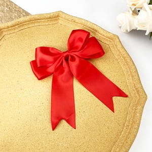 Détail d'une pince à cheveux nœud en satin rouge brillant sur un plateau doré élégant