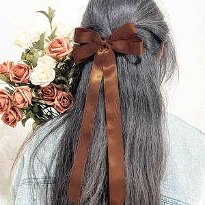 Détail de la pince à cheveux en satin marron avec de longs rubans sur les cheveux