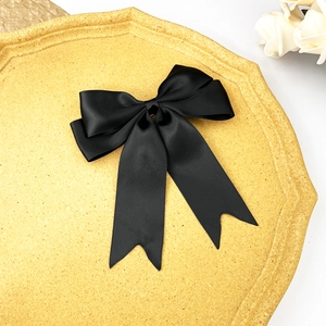 Barrette à nœud en satin noir sur plateau doré avec décoration de rose blanche