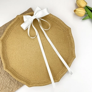 Close-up of white satin bow hair clip with long flowing ribbons on a brown tray