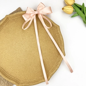 Detail of pink satin bow hair clip with long ribbons on a decorative stone plate