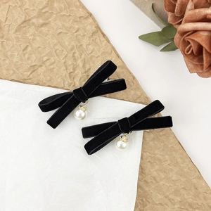 Détail de barrettes nœuds en velours avec pendentifs perles sur fond esthétique rétro