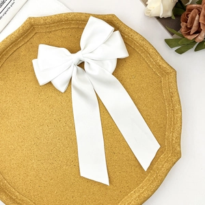Detail of elegant white satin bow hair clip with long ribbons on a decorative tray
