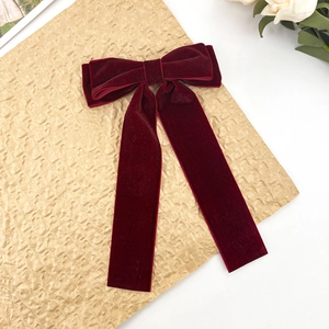 Elegant wine red velvet bow hair clip with long ribbons on a minimalist background