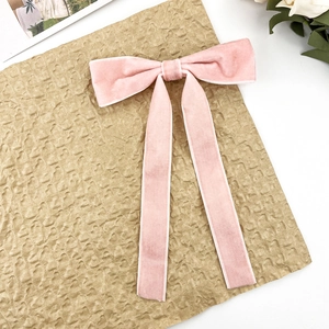 Detail of pink velvet bow hair clip with elegant long streamers and fine white stitched edges
