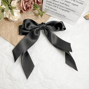 Détail d'un élégant nœud en satin noir avec de longs rubans sur un décor vintage