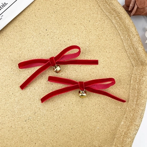 Dettaglio di fermagli per capelli a fiocco in velluto rosso con campanelli d'oro