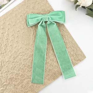 Detail of mint green velvet bow hair clip with long ribbons on vintage paper