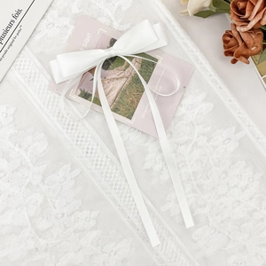 Détail du nœud en satin blanc avec longs rubans sur fond de dentelle et fleurs élégantes
