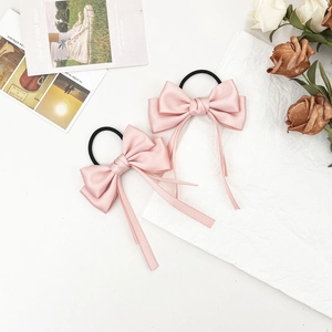 Close-up of pink silk satin bow hair scrunchies with long streamers and elastic band