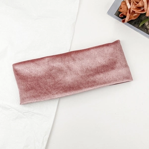 Detailed macro view of dusty pink velvet elastic headband on minimalist textured white background