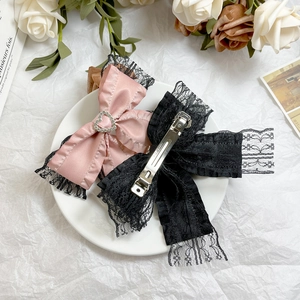 Elegant lace bow hair clips with heart rhinestones and satin detail on a white surface
