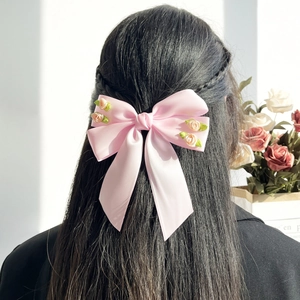 Fermaglio per capelli in raso rosa con rose e foglie decorative su capelli neri