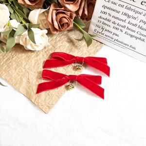 Detail of red velvet bow hair clips with gold bell charms and heart accents
