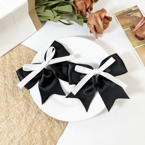 Detailed close-up of black and white ribbon bow hair clips on a white ceramic plate