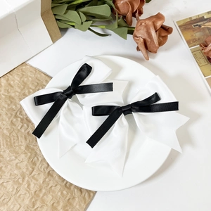Elegant set of two black and white layered ribbon bow hair clips on a white ceramic plate
