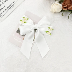 Dettaglio del fiocco in raso bianco con rose color crema e foglie in stile francese