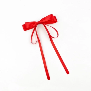 Détail d'une pince à cheveux nœud en satin rouge avec de longs rubans en soie
