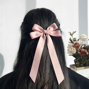 Nœud à cheveux en satin rose avec strass en cœur sur les cheveux noirs du modèle