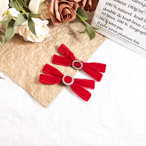 Detail of red velvet bow hair clips with sparkling rhinestone center on elegant background