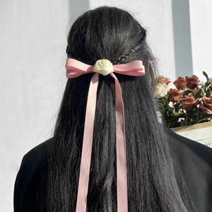 Nœud à cheveux rose avec rose crème et longs glands sur cheveux noirs
