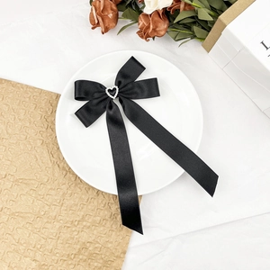 Barrette à cheveux élégante en satin noir avec perle en cœur sur une assiette blanche