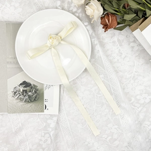 Vue détaillée d'un ruban en satin blanc crème avec un nœud rose sur une assiette en céramique