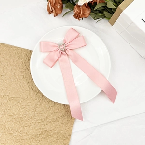 Détail du nœud rose en satin pour cheveux avec cristal en forme de cœur brillant