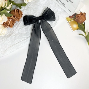 Detail of black mesh ribbon hair clip with rhinestones and elegant layered bow design