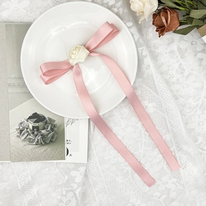 Détail du nœud en soie rose avec rose blanche délicate sur fond de dentelle blanche