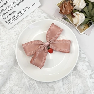 Détail d'un nœud papillon en satin rose avec bords volantés et un pendentif fraise réaliste