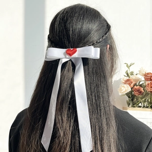 Elegante fermaglio per capelli con fiocco bianco e cuore rosso su capelli scuri