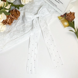 Detail of white mesh bow hair clip with sparkling rhinestones and long elegant ribbons